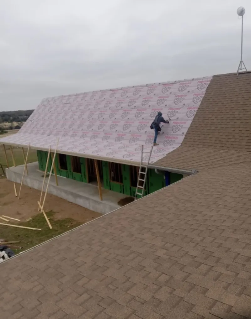Worker preparing underlayment for a metal roof installation in Gaines